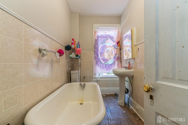 bathroom with a tub, sink, tile walls, and hardwood / wood-style flooring