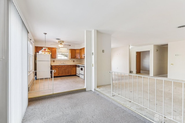 interior space with white appliances, sink, pendant lighting, light carpet, and tasteful backsplash