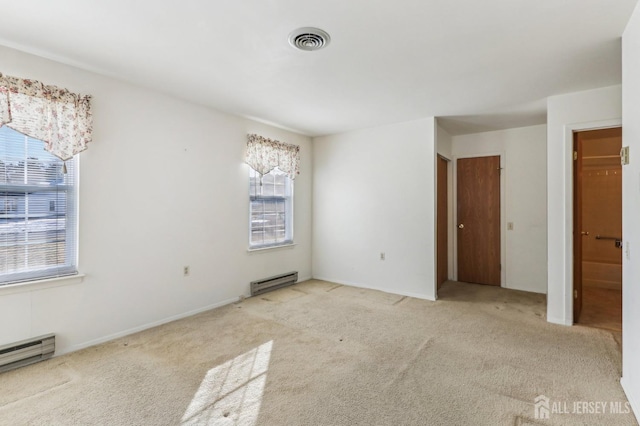 spare room featuring light carpet and baseboard heating