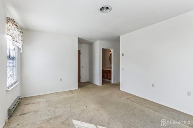 carpeted spare room with a baseboard heating unit