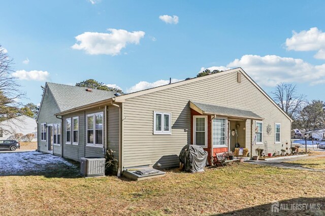 rear view of property with central AC and a lawn