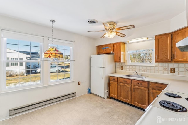 kitchen with white fridge, sink, plenty of natural light, hanging light fixtures, and baseboard heating