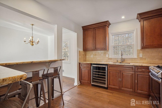 kitchen with beverage cooler, backsplash, stainless steel range with gas cooktop, and sink