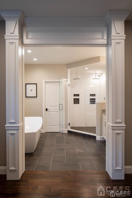 bathroom with independent shower and bath, hardwood / wood-style flooring, and decorative columns