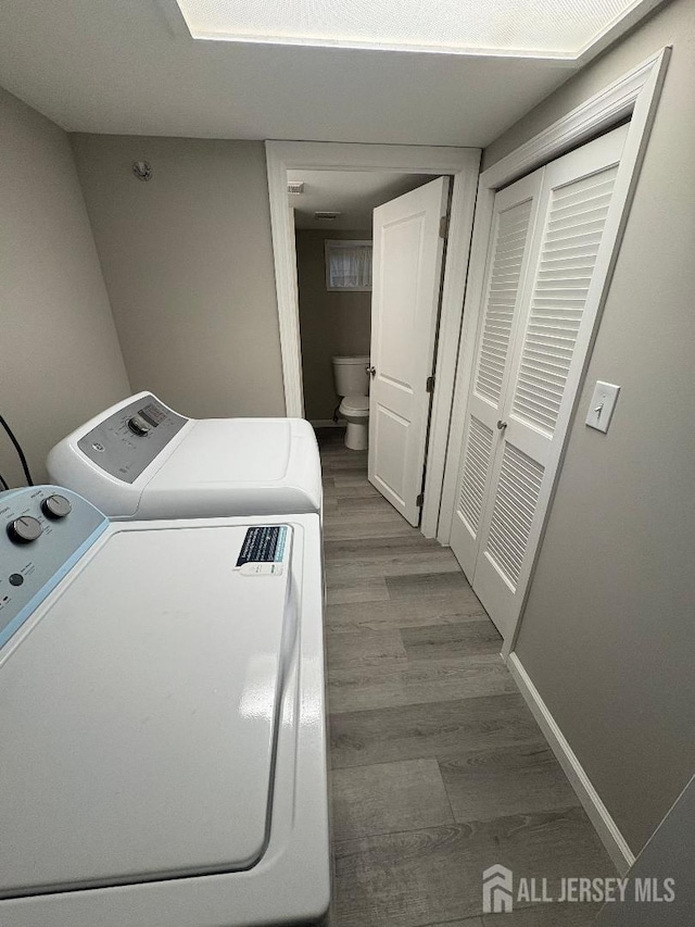laundry room featuring separate washer and dryer, laundry area, and wood finished floors
