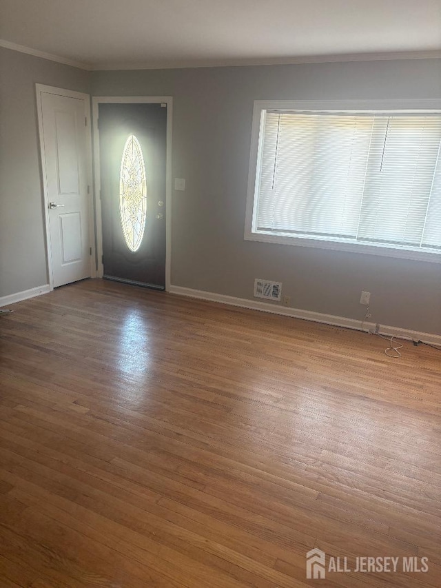 entrance foyer featuring ornamental molding, baseboards, visible vents, and wood finished floors