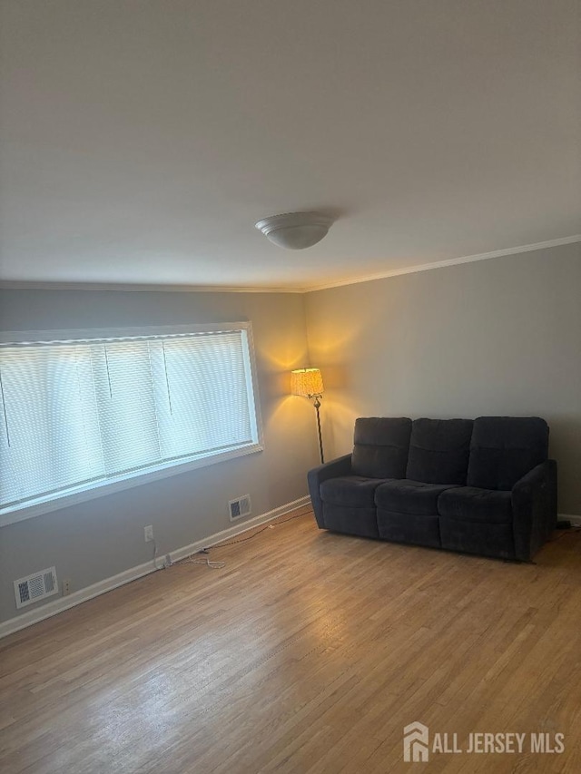 living room featuring ornamental molding, baseboards, visible vents, and wood finished floors