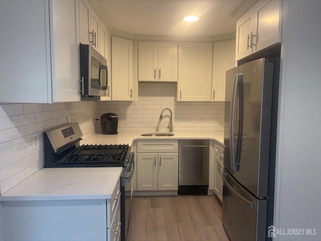 kitchen featuring white cabinetry, stainless steel appliances, a sink, and wood finished floors
