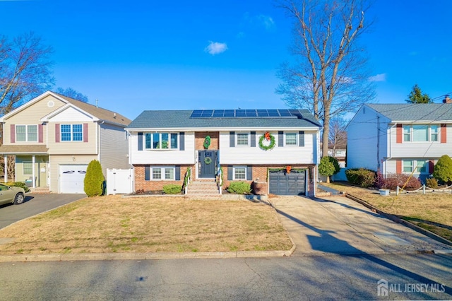 split foyer home with a front lawn, a garage, and solar panels