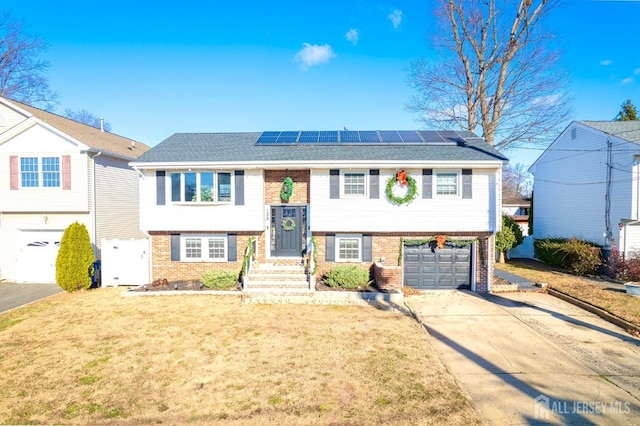 split foyer home with solar panels, a garage, and a front lawn