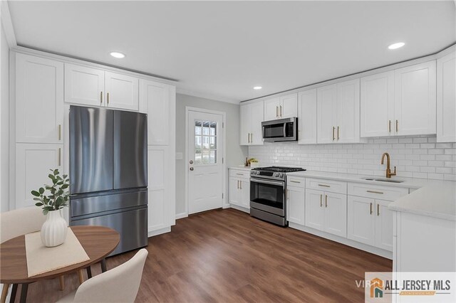 1092 Woodruff St, Iselin, NJ 08830 - kitchen with stainless steel appliances, a sink, light countertops, dark wood finished floors, and backsplash