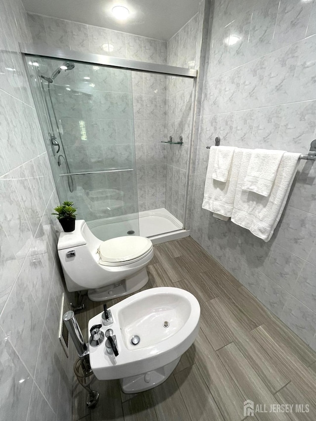 bathroom with toilet, a sink, a bidet, tile walls, and a shower stall