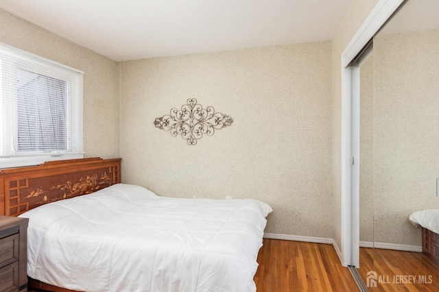 bedroom featuring wood finished floors, a closet, and baseboards