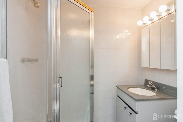 bathroom featuring a shower stall, tile walls, and vanity