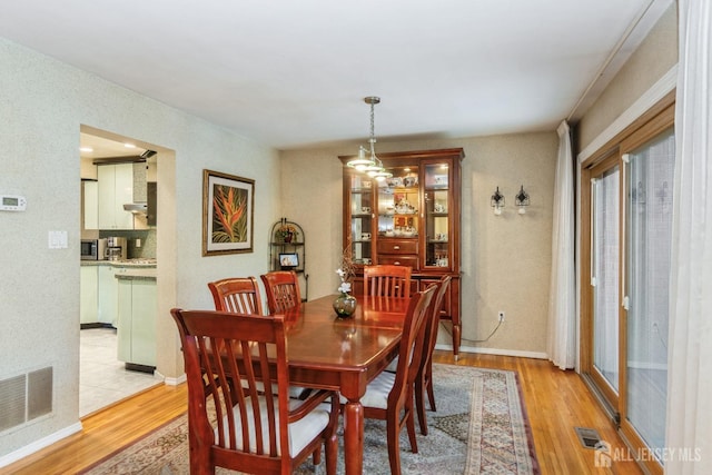 dining area with light wood-style flooring, baseboards, and visible vents