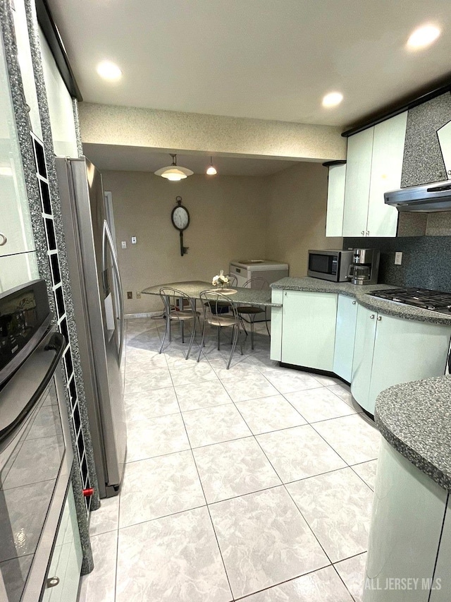 kitchen featuring dark countertops, range hood, white cabinetry, stainless steel appliances, and light tile patterned floors