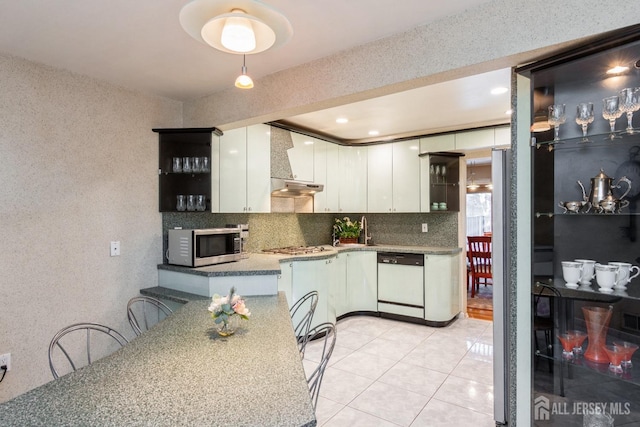 kitchen with decorative backsplash, under cabinet range hood, white cabinets, and appliances with stainless steel finishes