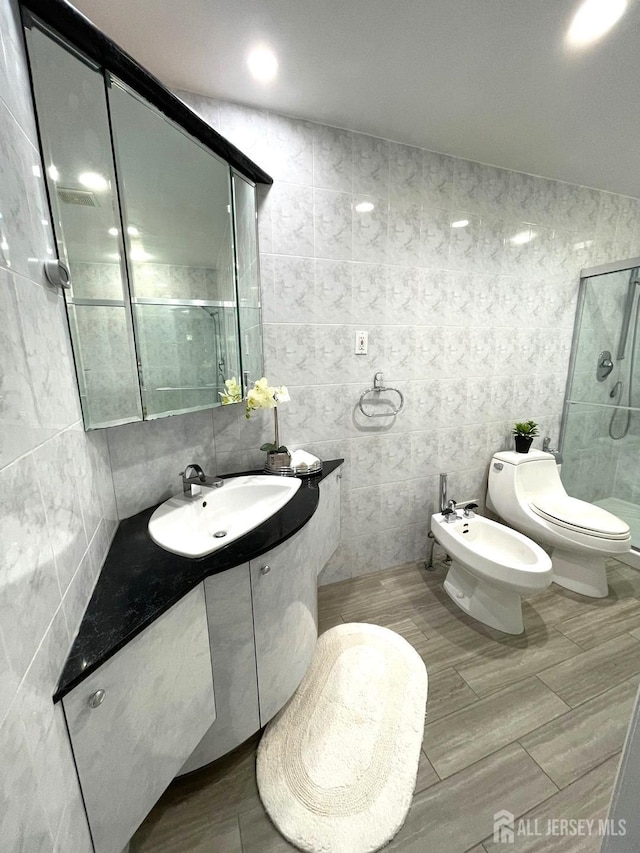 bathroom with toilet, a stall shower, a bidet, tile walls, and vanity