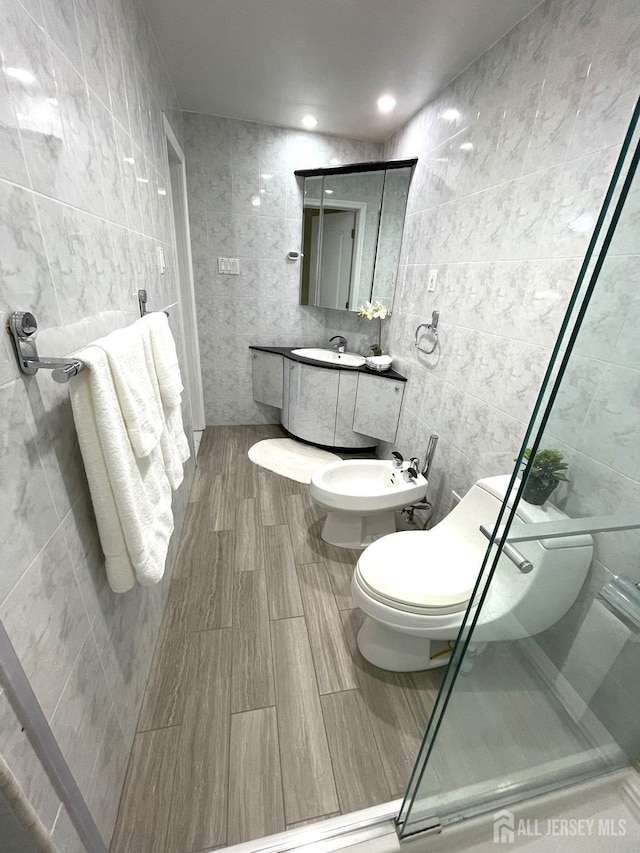 full bathroom featuring tile walls, a bidet, a shower stall, and a sink