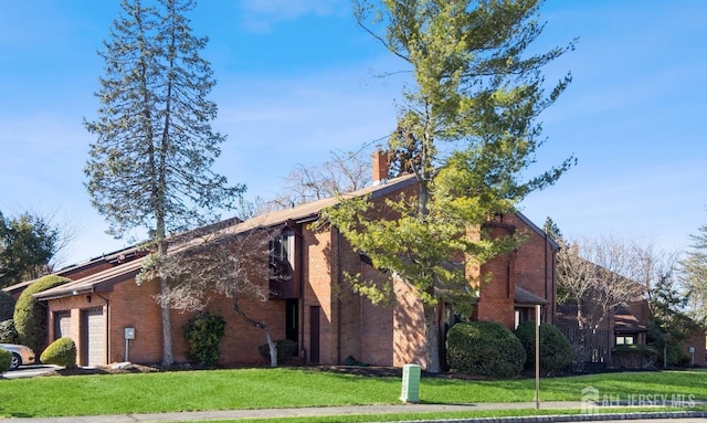 view of side of home featuring brick siding, an attached garage, and a lawn