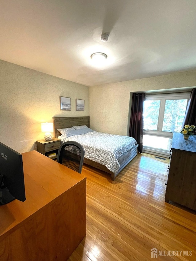 bedroom featuring a textured wall and hardwood / wood-style flooring