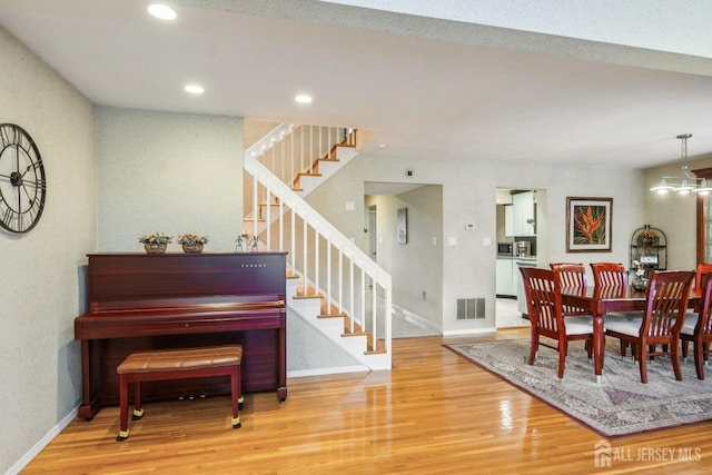 dining area with visible vents, baseboards, wood finished floors, and stairway