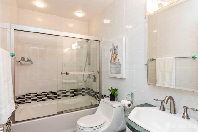 bathroom with combined bath / shower with glass door, a sink, tile walls, toilet, and tasteful backsplash