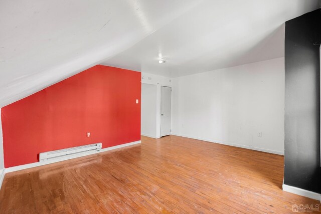 bonus room featuring light hardwood / wood-style floors, vaulted ceiling, and a baseboard heating unit