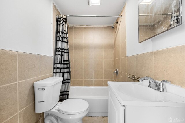 full bathroom featuring vanity, toilet, shower / bathtub combination with curtain, and tile walls