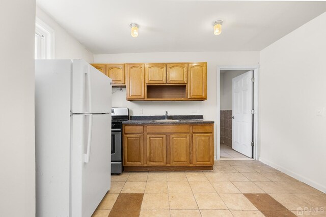 kitchen with sink, light tile patterned floors, stainless steel range oven, and white refrigerator