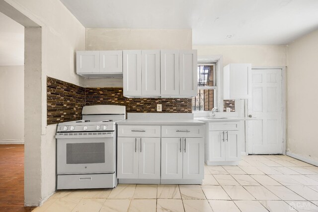 kitchen featuring decorative backsplash, white range oven, white cabinetry, and sink