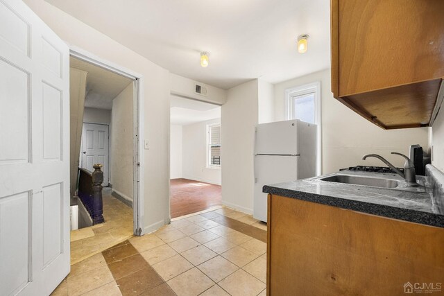 kitchen featuring white fridge, light tile patterned flooring, and sink