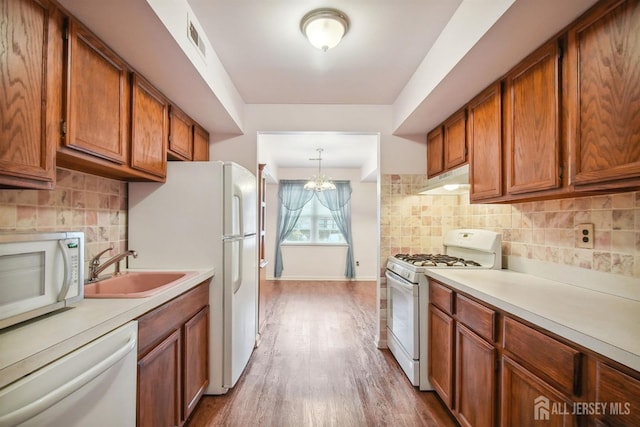 kitchen with white appliances, visible vents, light countertops, under cabinet range hood, and brown cabinets