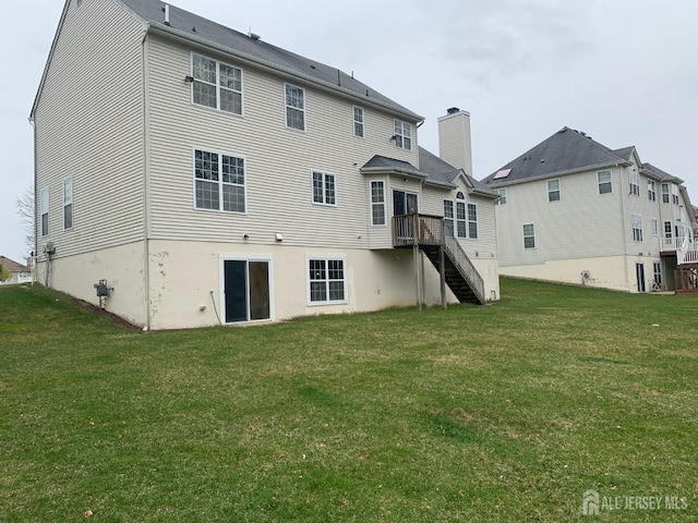 rear view of property with stairway and a lawn