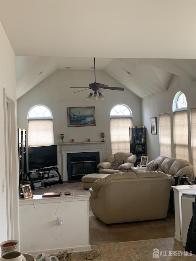 living area featuring a glass covered fireplace, ceiling fan, and lofted ceiling