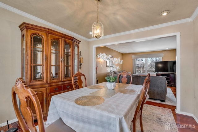 dining space featuring baseboards, wood finished floors, an inviting chandelier, and crown molding