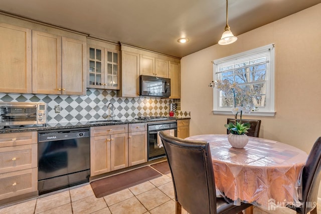 kitchen with a sink, dark countertops, black appliances, light tile patterned flooring, and backsplash