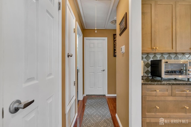 hall featuring attic access, a toaster, and baseboards