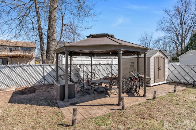 view of yard featuring an outdoor structure, a fenced backyard, a gazebo, a storage shed, and a patio area