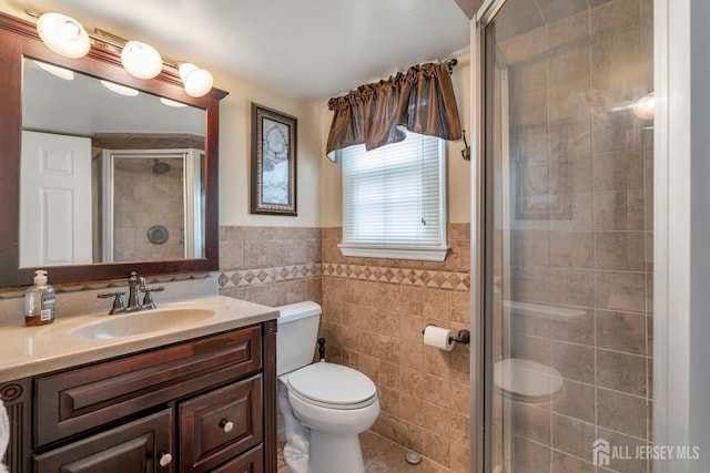 full bath featuring tile patterned floors, a shower stall, tile walls, toilet, and vanity