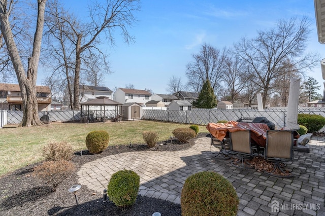 view of patio featuring a residential view, a fenced backyard, a shed, outdoor dining space, and a gazebo