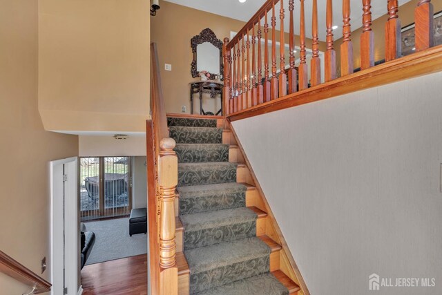 stairs featuring a towering ceiling and wood finished floors