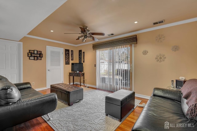 living area with ornamental molding, ceiling fan, light wood finished floors, baseboards, and visible vents