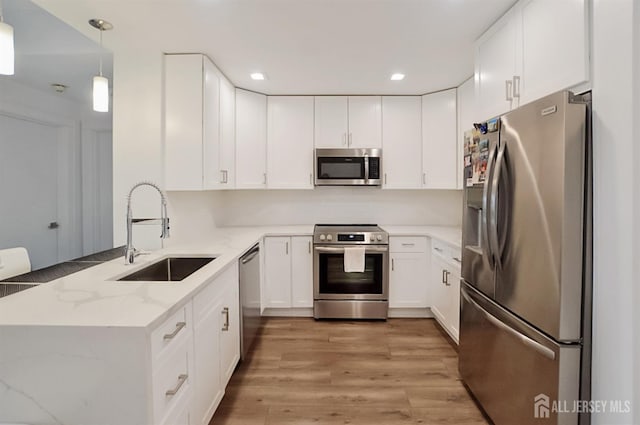 1 Carriage City Plz Unit 509, Rahway, NJ 07065 - kitchen featuring appliances with stainless steel finishes, a peninsula, light stone countertops, light wood-style floors, and white cabinets
