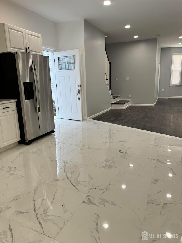 kitchen featuring stainless steel refrigerator with ice dispenser and white cabinetry