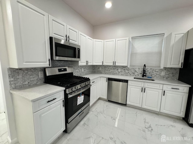 kitchen with decorative backsplash, appliances with stainless steel finishes, white cabinetry, and sink