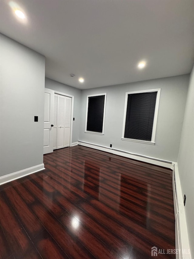 empty room featuring hardwood / wood-style floors and a baseboard heating unit