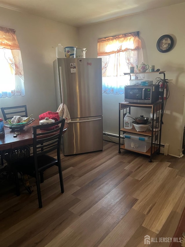 kitchen with hardwood / wood-style flooring, a baseboard radiator, and appliances with stainless steel finishes