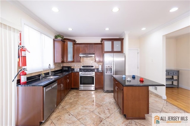 kitchen with glass insert cabinets, dark countertops, stainless steel appliances, and under cabinet range hood