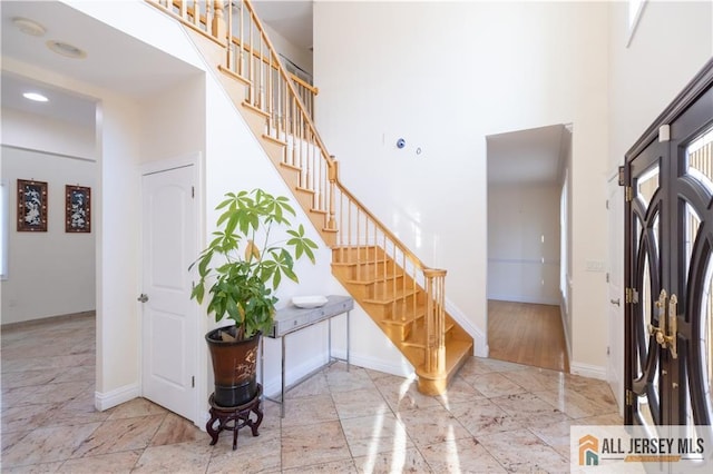 entryway featuring stairway, a high ceiling, and baseboards